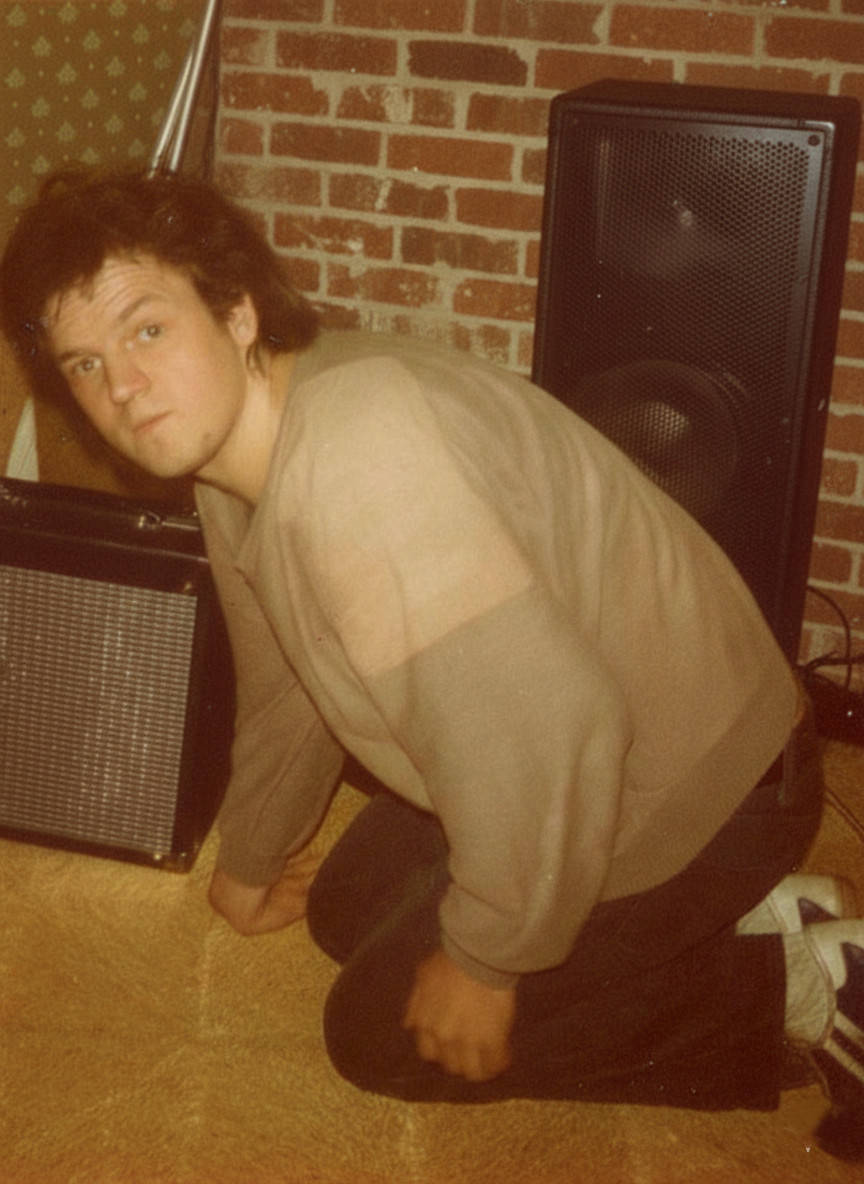 Che Guitare präsentiert seinen damals neuesten, selbstgebauten Gitarrenverstärker. Hinter ihm steht eine ebenfalls selbstgebaute PA-Lautsprecherbox.